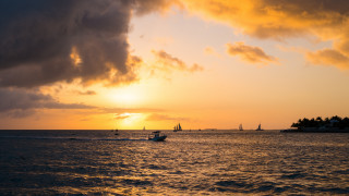 Boat sunset clouds island water - a small island in the distance free wallpaper