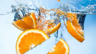Orange slice dropped into water - cut free wallpaper