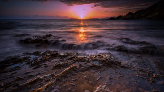 Sunset ocean waves rocks mountain - a mountain in the distance free wallpaper