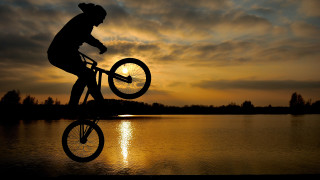 Sunset bike over lake horizon - the sun in the background free wallpaper