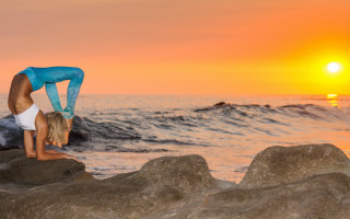 Woman handstand rock ocean sunset - the sun setting behind her free wallpaper