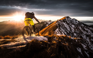 Man bike snow sunset mountains - the sun shining behind free wallpaper