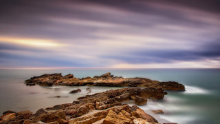 Rocky shore ocean mountains sunset - rich moody colours free wallpaper