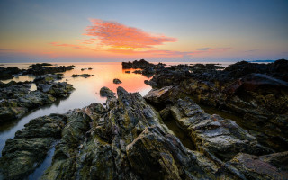 Sunset rocky beach water bridge - a sunset over a rocky beach free wallpaper