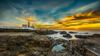 Lighthouse rocky shore sunset clouds 8 - a lighthouse free wallpaper