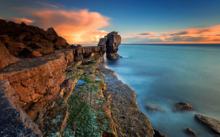 Rocky cliff water sunset clouds 2 - the foreground and a sunset in the background free wallpaper