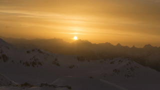 Sunset mountains snow clouds beach - a sunset over a mountain range free wallpaper