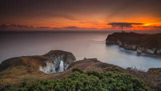Sunset cliff lighthouse water beach - a sunset over a rocky cliff free wallpaper