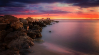 Sunset rocky beach lighthouse water - rich moody colours free wallpaper