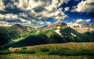 Mountain range clouds grassy field - a grassy field below free wallpaper