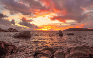 Sunset ocean rocks mountains cloudy - the foreground and a mountain in the background free wallpaper for desktop