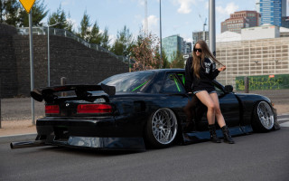 Woman blackcar crossedlegs outdoor cityscape - clean line free wallpaper