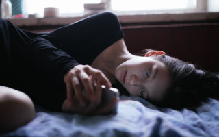 Woman lying bed holding phone - a bed holding free wallpaper