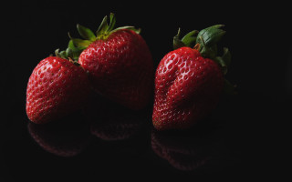 Three strawberries black surface reflection - a reflection of them free wallpaper