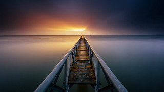 Pier ocean sunset sky water - a bright sun in the distance free wallpaper