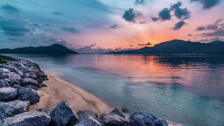 Beach rocks water sunset mountains - rock and water under a cloudy sky free wallpaper