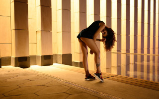 Woman leaning wall skirt sneakers - her leg up free wallpaper