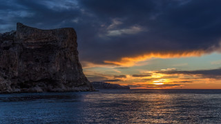 Rock outcropping sunset ocean boat - a large rock free wallpaper