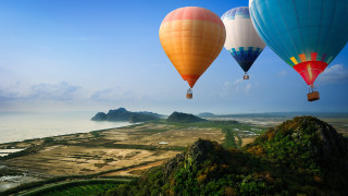 Hot air balloons mountain ocean - a small island in the distance free wallpaper