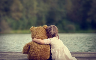 Little girl hugging teddy bear 2 - the background and a forest in the background free wallpaper