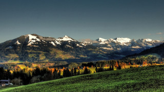 Mountain range forest lake sunset 5 - a green field in the foreground free wallpaper