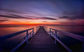 Sunset pier mountain ocean water - a boat in the distance free wallpaper