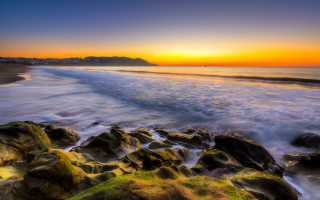 Sunset beach rocks water city - a city in the distance free wallpaper for desktop