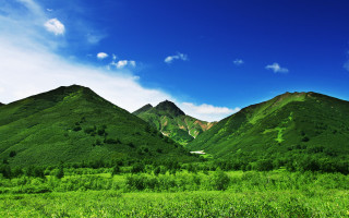 Green mountain range blue sky 6 - a green field in the foreground free wallpaper