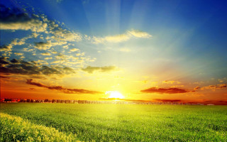 Sunrise field clouds mountains ocean - a bright sun in the background free wallpaper