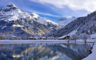 Mountain lake houses snowy sky - the foreground and a snow free wallpaper