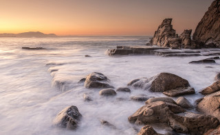 Rocky beach sunset island ocean - a small island in the distance free wallpaper