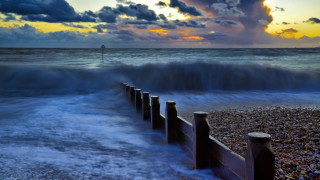 Wave fence beach sunset lighthouse - a lighthouse in the distance free wallpaper