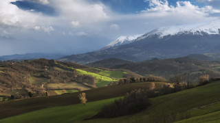 Mountain range snow capped green - a green field in the foreground free wallpaper