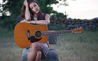 Woman sitting guitar rock background - a tree in the background free wallpaper