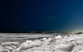 Snowy beach night city bright - a bright light in the distance free wallpaper