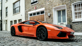 Bright orange sports car cobblestone 2 - a brick building free wallpaper