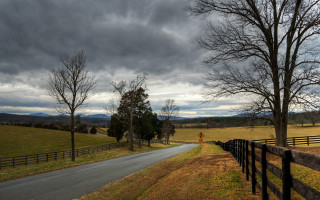 Stormy road fence trees sky - a road sign free wallpaper