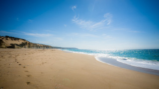 Sandy beach footprints blue sky - free beach wallpaper
