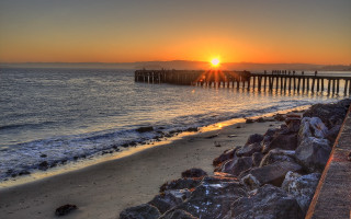 Sunset beach pier rocks ocean - a pier in the background free wallpaper