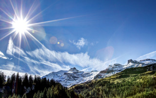 Sun mountain pine snowlight blue - over a mountain range free wallpaper