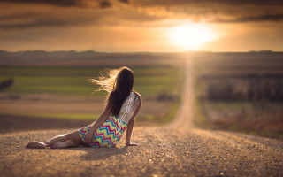 Girl sitting road sunset blowing - the sun setting behind her free wallpaper