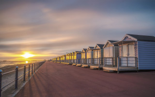 Beach huts sunset ocean tilt - the sun setting behind them free wallpaper