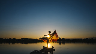 Dusk sunset flag person dock - the sun setting behind them free wallpaper for desktop