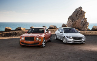 Two luxury trucks rocky beach - two car free wallpaper