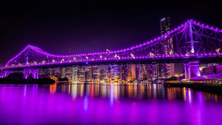 Purple lit bridge night cityscape - over a body of water free wallpaper