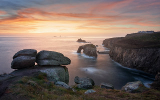 Rocky cliff sunset water boat - a boat in the distance free wallpaper