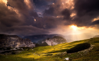 Mountain grassy field cloudy sky 3 - a sunbeam in the distance free wallpaper