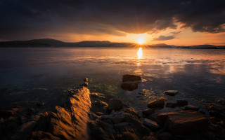 Sunset water rocks mountains city - a sunset over a body of water free wallpaper