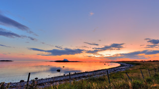 Sunset water fence hill cityscape - a sunset over a body of water free wallpaper for desktop