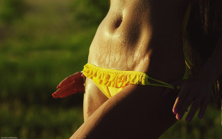 Woman yellow bikini frilly posing - shiny skin free wallpaper